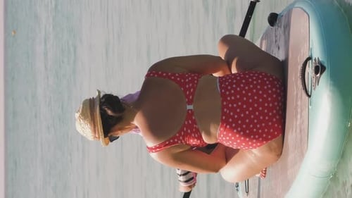 Woman Paddling on Paddle Board in Swimsuit on Ocean