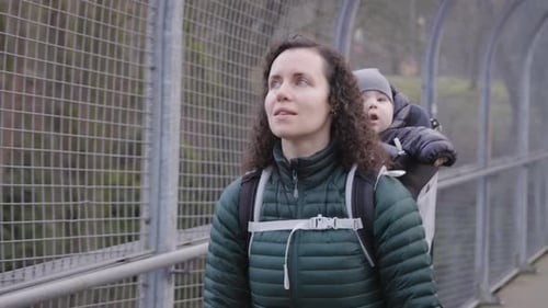 Mère et joli petit garçon en porte-bébé marchant le long du chemin du parc marin d'Inlet Barnet en hiver