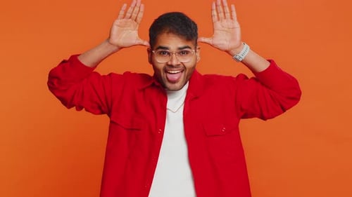 Silly Young Adult Posing on Orange Background
