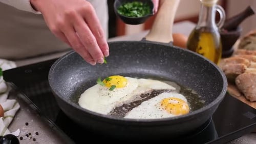 Adding Herbs to Fried Eggs in Pan