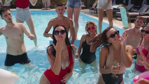 Men and Women at Party in Swimming Pool with Clear Blue Water and Inflatable Tubes Dance Sunbath