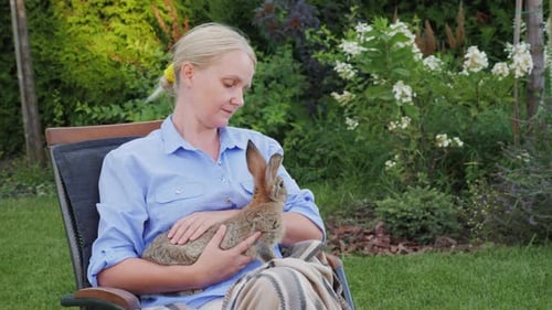 Woman Cradles Rabbit in Sunny Garden Setting
