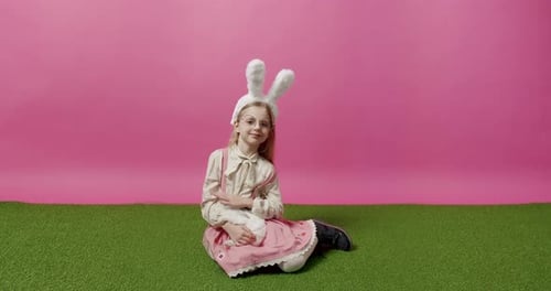 Blond Girl Cuddles White Rabbit on Green Grass