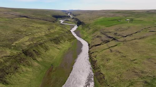 Aerial view of waterfall in lush valley, Iceland.