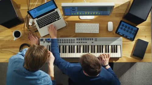 Top View of Two Audio Engineers Working in Their Sunny Studio. They Play on a Musical Keyboard and