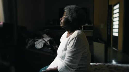Thoughtful Senior Woman Sitting on Bed in Bedroom