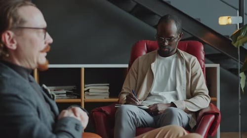 Two Men Discussing and Writing in Modern Office