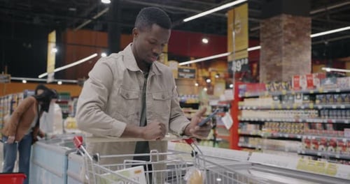 Man Shops, Uses Smartphone in Modern Supermarket
