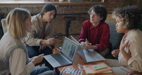 Creative Team: Entwickler mobiler App sprechen im Gespräch auf den Laptop-Bildschirm und arbeiten gemeinsam im Café