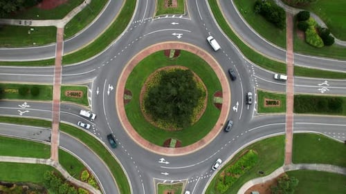 Top down view of cars driving around traffic circle - rotating aerial shot.