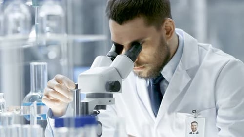 Research Scientist Adjusts His Microscope. He's Working in a High-End Modern Laboratory with Beaker