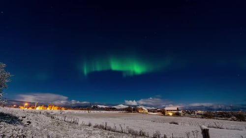 time lapse of bright northern lights over village in norway during winter night