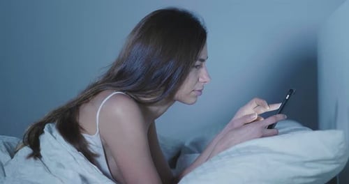 Beautiful woman in bed, use the phone before falling asleep, send messages, watch social networks.