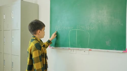 Junge schreiben gerne seinen Namen auf die grüne Tafel und buchstabieren sie auch vor dem Klassenzimmer der Heimschule.