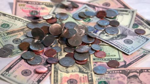 American money falling onto a marble countertop.