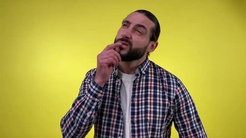 Man Ponders, Scratches Head in Front of Yellow Background
