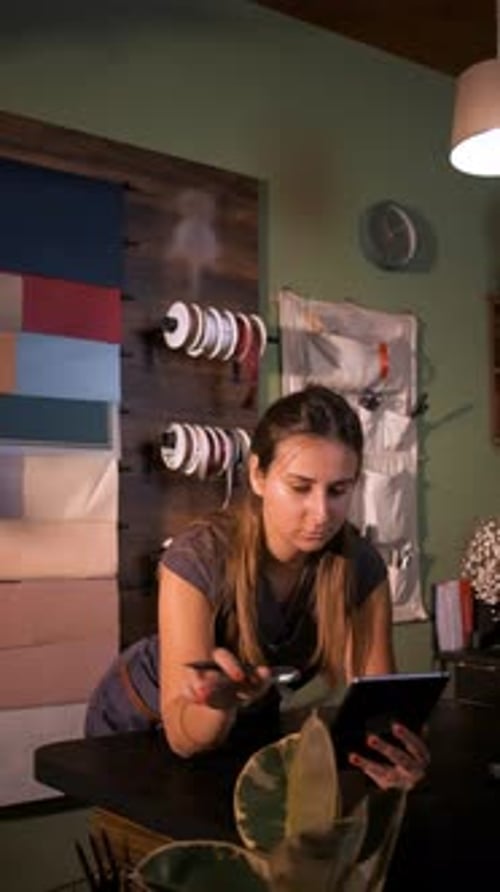 Vertical video of young woman working in her flower shop using tablet.