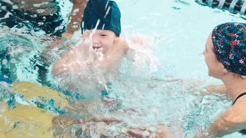 Toddler Boy Learns Swimming and Enjoys the Water Activity in the Public Pool with His Mother