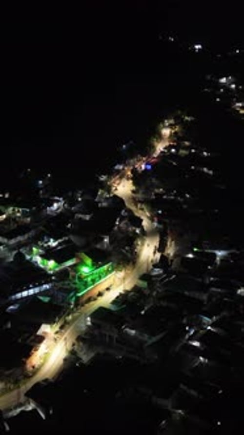 Vertical drone footage of the vehicles driving on illuminated highway roads in the city at night