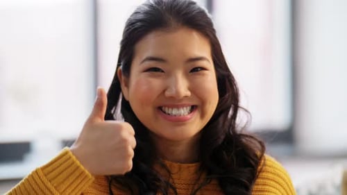 Menschen-, Ethnizitäts- und Rassenkonzept - Porträt einer glücklich lächelnden asiatischen jungen Frau mit erhobenen Daumen