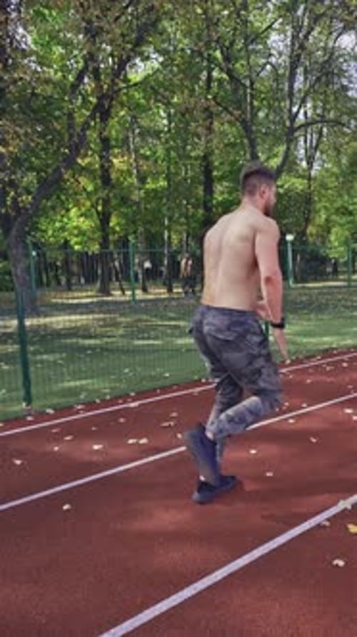 Sport man running on racetrack. View of athletic shirtless sportsman running on track