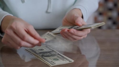 Woman Counting One Hundred Dollar Bills on Desk