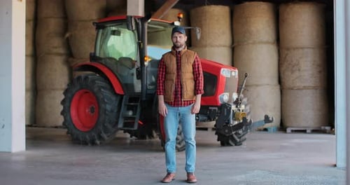 Farmer Standing in Front of Tractor in Barn