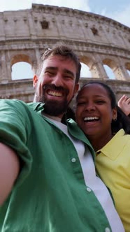Smiling couple takes selfie in front of coliseum