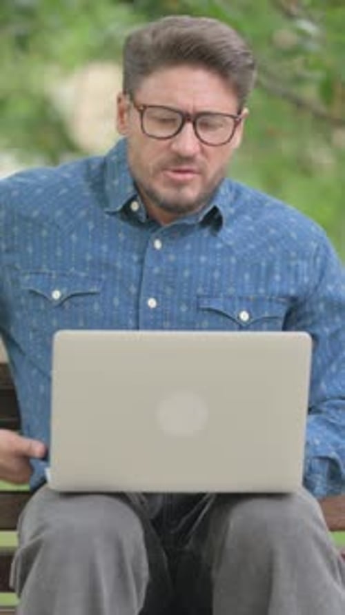 Man Working on Laptop Outdoors Experiences Back Pain