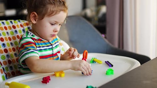 Young Child Plays with Colorful Modeling Clay at Home