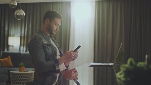 Adult Using Smartphone and Laptop at Home