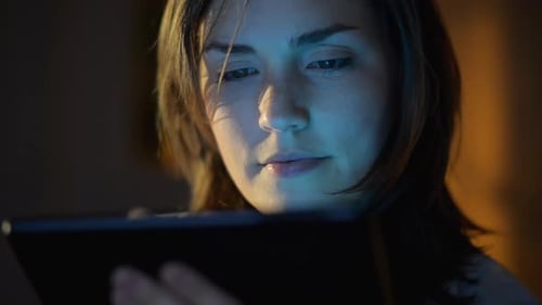 4k video footage of a young woman using a digital tablet late at night