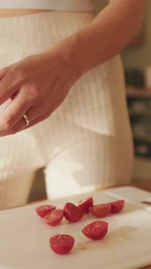 Close-up of young woman's hands cutting tomatoes making salad at home in the kitchen