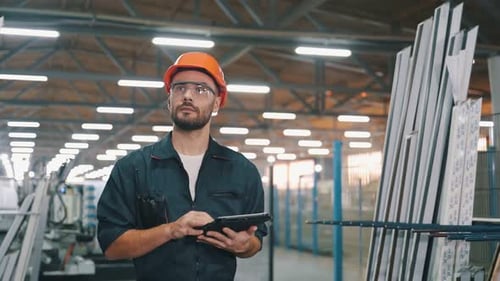 Worker with Black colored tablet in hands. Man is walking in the modern factory.