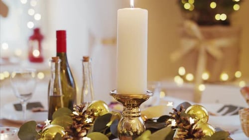 Close-Up Of Candle On Table Set For Dinner Meal At Christmas Time.