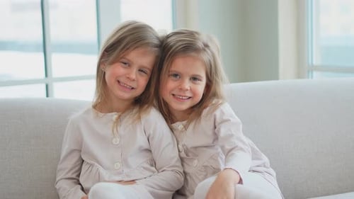 Happy Young Sisters Smiling on Gray Couch
