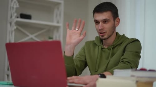 Portrait of Positive Confident Man Waving Greeting in Video Chat on Laptop Sitting in Home Office