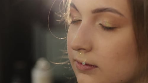 Applying Makeup to Young Woman's Eyelid with Brush