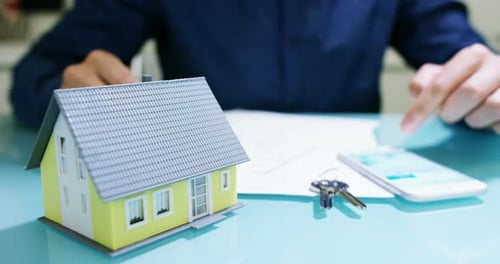 Real Estate Professional Using Smartphone with Miniature House