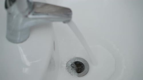 Water Flowing from Chrome Faucet into Sink
