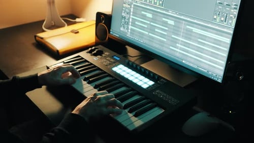 Music production. Man playing a MIDI keyboard. Home studio