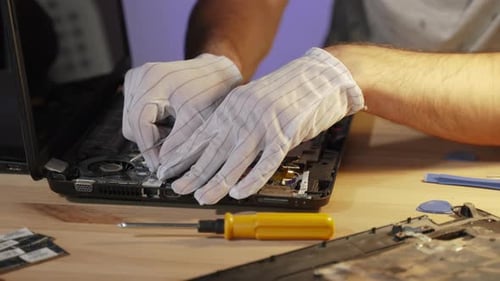 Un trabajador de servicio con guantes desconecta el cable del enfriador en un primer plano de una computadora portátil