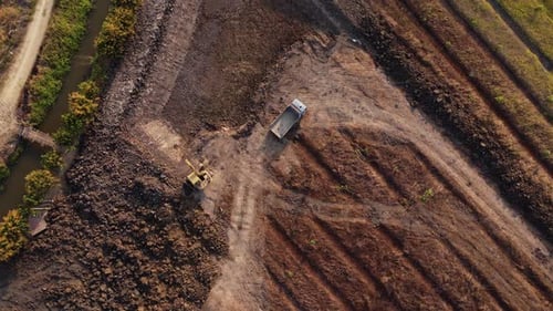 Aerial view of a wheel loader excavator with a backhoe loading sand into a heavy earthmover