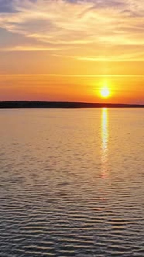 Beautiful sunset is reflecting in the river. Sunset lake landscape. Colorful sky. Vertical video