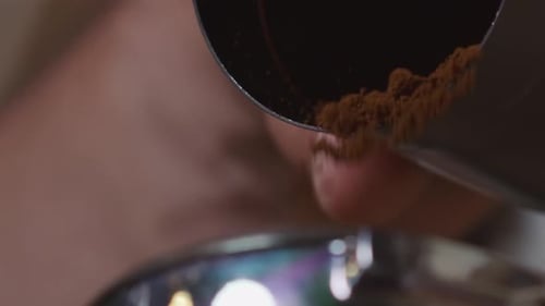 Slow motion close-up footage from the powder of ground coffee beans falling slowly ready to prepare