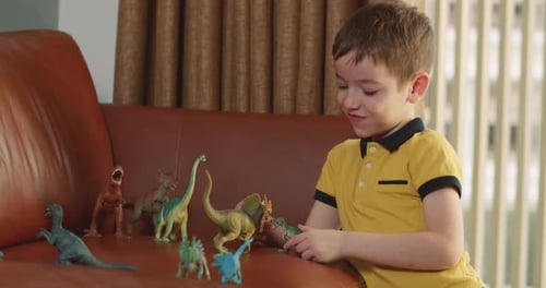 Young Boy Plays with Dinosaur Figurines on Couch
