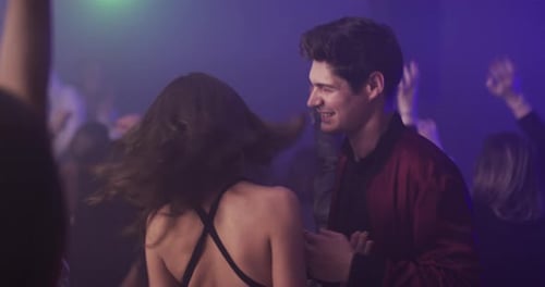 Young Adults Dancing in Colorful Nightclub Environment