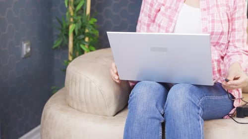 Woman Working on Laptop at Home, Plugs Charger