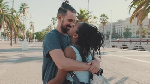 Familia interracial feliz abrazándose y besándose afuera