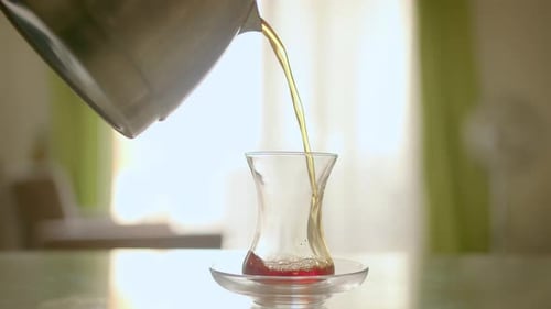 Eine Glasschale für Tee mit Untertasse steht auf dem Tisch vor dem Hintergrund des Fensters